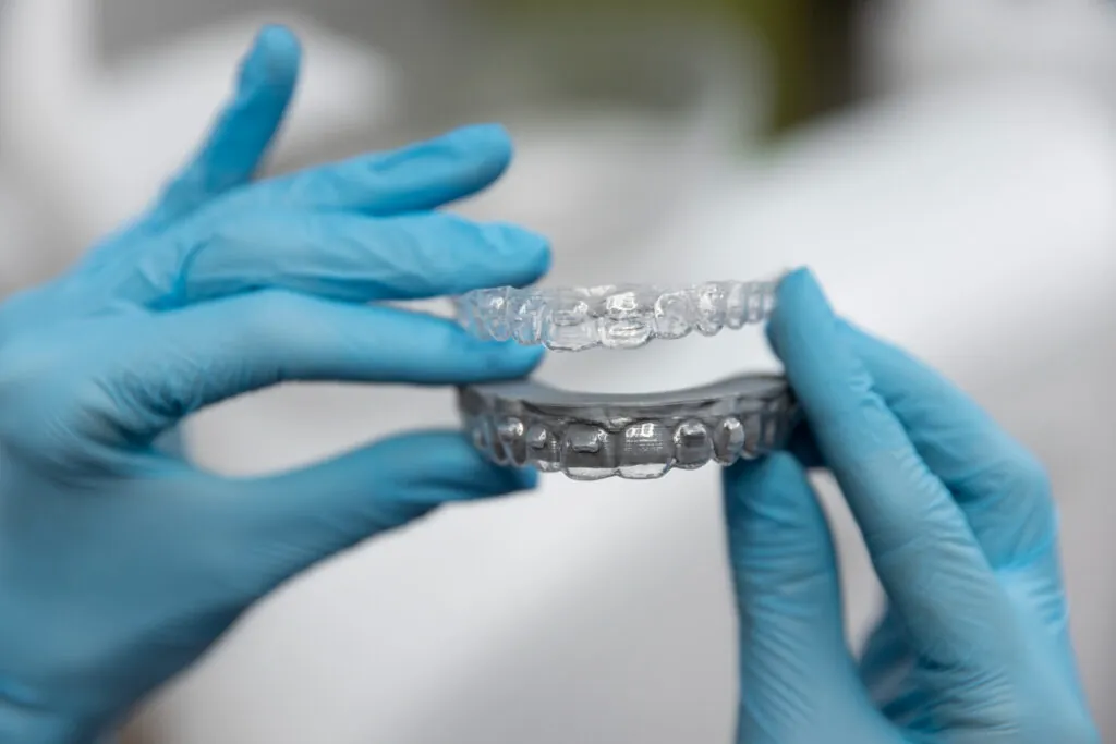 Gloved hands holding a clear aligner tray